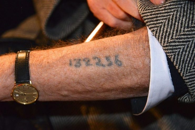 A Holocaust survivor displaying his arm tattoo Photo by Frankie Fouganthin -CC BY-SA 3.0