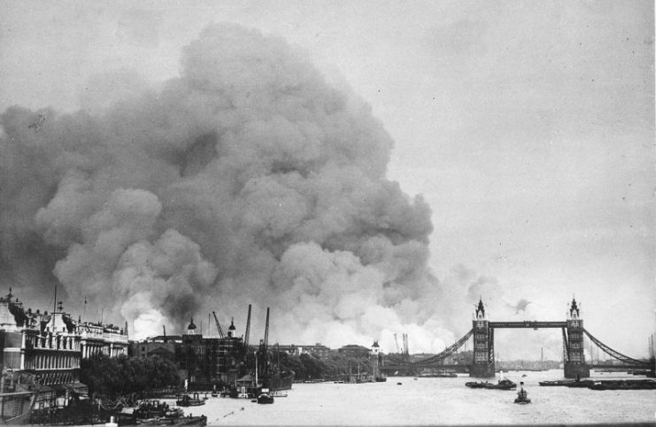 View along the River Thames in London towards smoke rising from the London docks after an air raid during the Blitz.