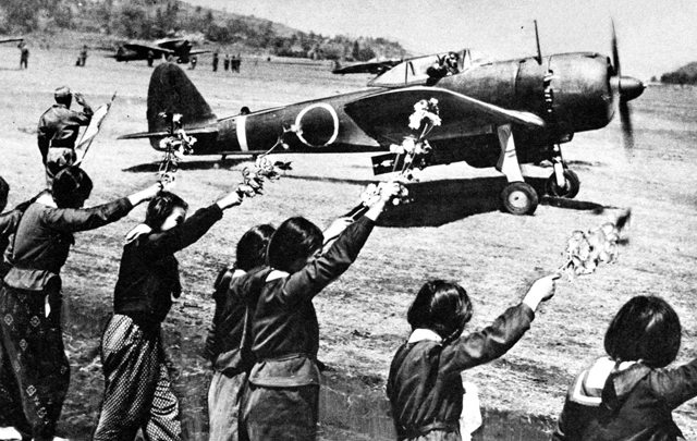 Chiran high school girls wave farewell with cherry blossom branches to departing kamikaze pilot in a Nakajima Ki-43-IIIa Hayabusa.