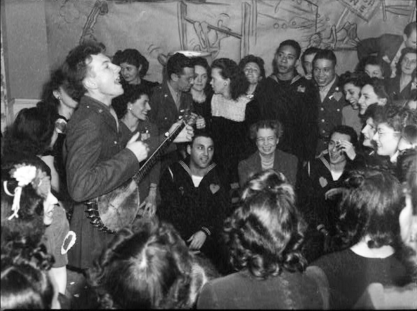 Pete Seeger entertaining Eleanor Roosevelt (center), honored guest at a racially integrated Valentine’s Day party marking the opening of a Canteen of the United Federal Labor, CIO, in then-segregated Washington, D.C., 1944.
