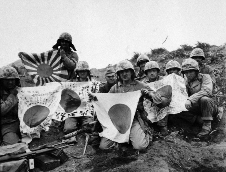 5th Division Marines grounded behind their light machine gun, display Japanese battle flags captured during the first few days of the fighting on Iwo Jima. Photographed by Farnum, February 1945. Official U.S. Marine Corps photograph, now in the collections of the National Archives.