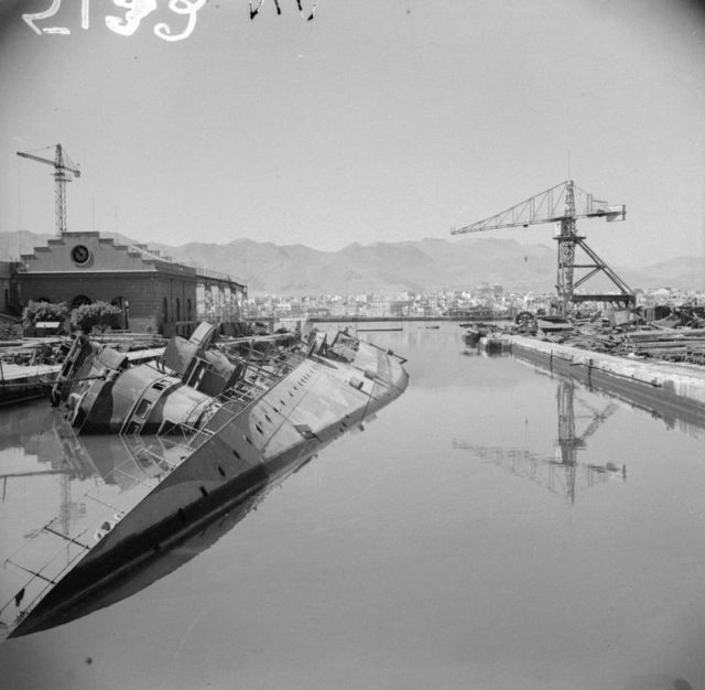 Italian gunboat ‘Geniere’ lies on its side in Palermo Harbour after being hit by a bomb, 23-26 July 1943. The Americans entered Palermo on 22 July, cutting off 50,000 Italian troops in the west of the island. But the mobile Axis forces, including most of the Germans, escaped to the north-east corner of the island. [© IWM (NA 5132)]