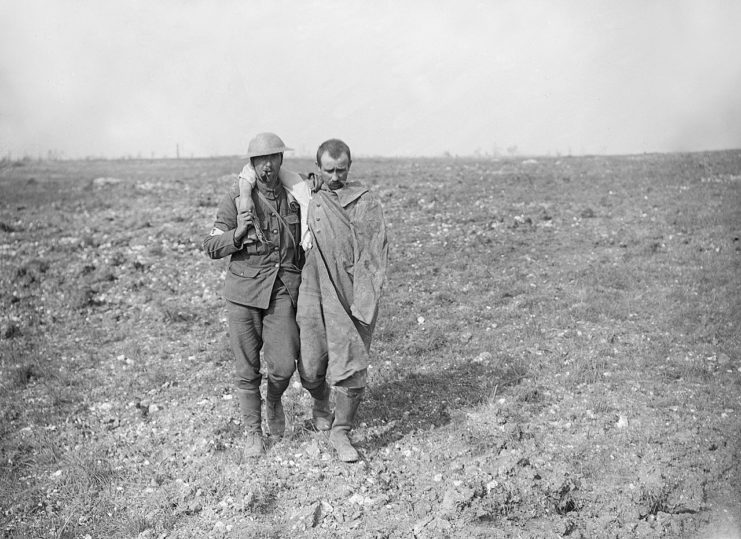 British soldier helping a wounded German prisoner across open country. Ginchy, 25 September.