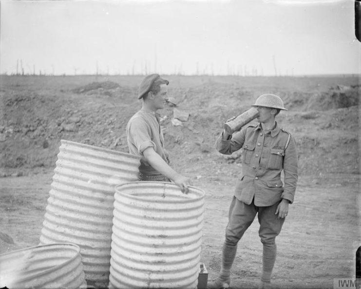 Water butts at Ginchy. A British soldier using a shell case as a drinking cup. September 1916.