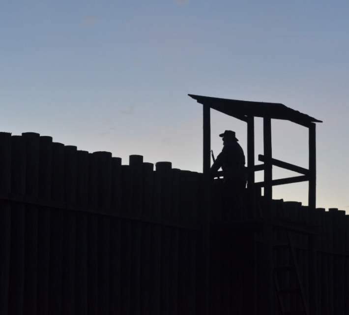 A volunteer reenacts a guard standing watch over the prison at dusk. 