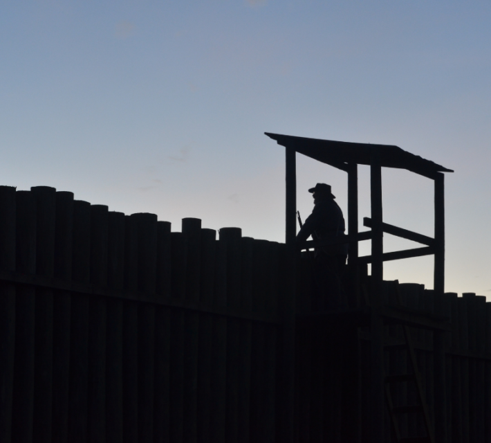A volunteer reenacts a guard standing watch over the prison at dusk.