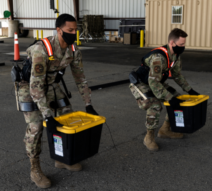 Porters using exoskeletons to assist in lifting boxes