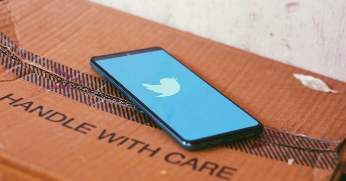 phone displaying Twitter logo on box that says handle with care
