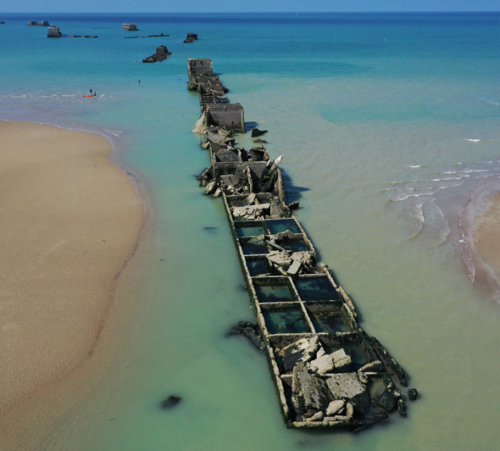 aerial view pieces of the World War II Allied temporary Mulberry harbor built during the D-Day invasion lie in the water at Asnelles on April 30, 2019 at Arromanches-les-Bains, France