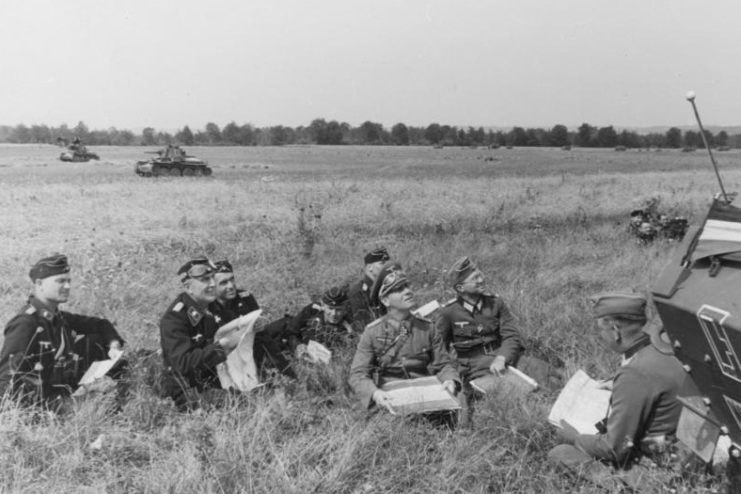 Rommel and his staff sitting in the grass with paper in their hands