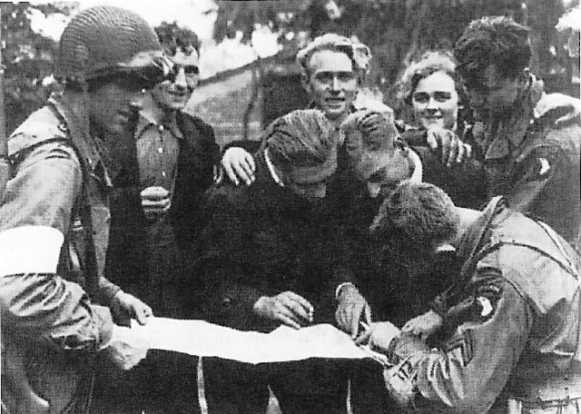Members of the Dutch Resistance looking over a map with members of the 101st Airborne Division