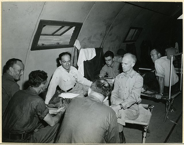 Ernie Pyle and combat photographers sitting on cots
