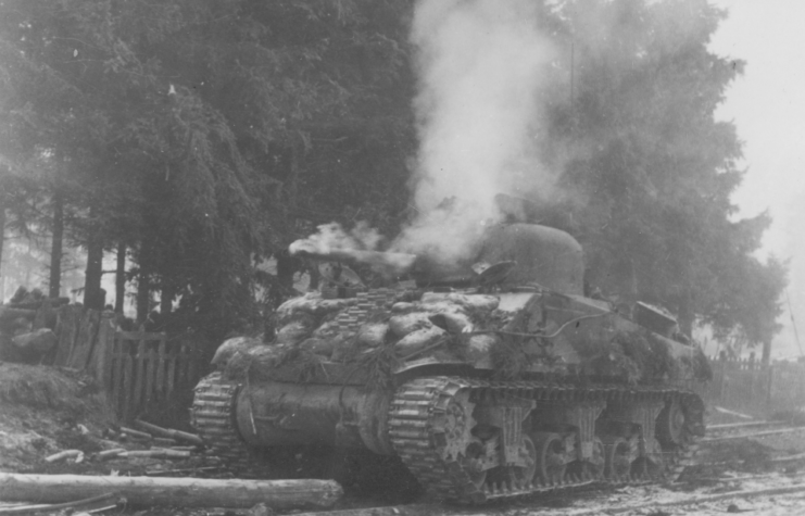 A blazing Sherman tank abandoned during the Battle of the Bulge