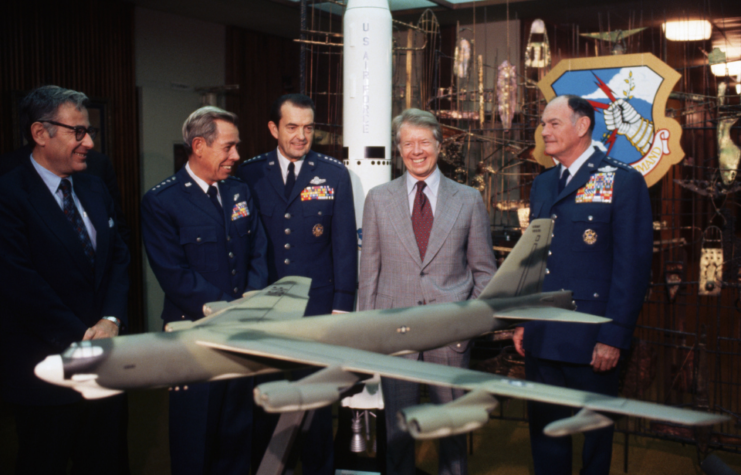 President Jimmy Carter and his Secretary of Defense, Harold Brown, view a model B-52 at Offutt Air Force Base in Nebraska, accompanied by Air Force officers.