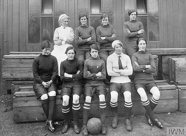 Nine female soccer players sitting on wooden bleachers