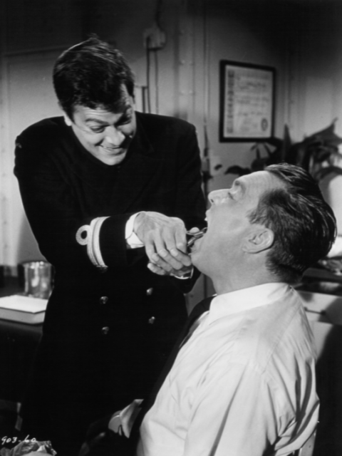 Tony Curtis pulling out tooth of Edmond O'Brien in a scene from the film 'The Great Impostor', 1961.