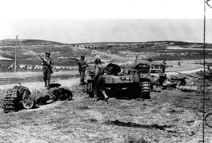 American soldiers walking around a damaged German tank