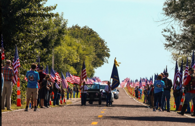 Motorcade lined with American flags and people