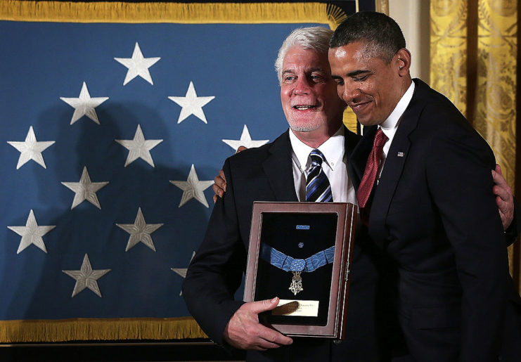Ray Kapaun holding the Medal of Honor with President Barrack Obama standing beside him
