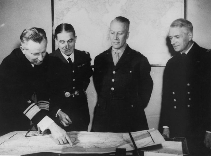 Rear Admiral A.C. Bennett, General Alain de Boissieu, Major-General Lloyd Fredendall and Admiral André Georges Rioult looking at documents on a table