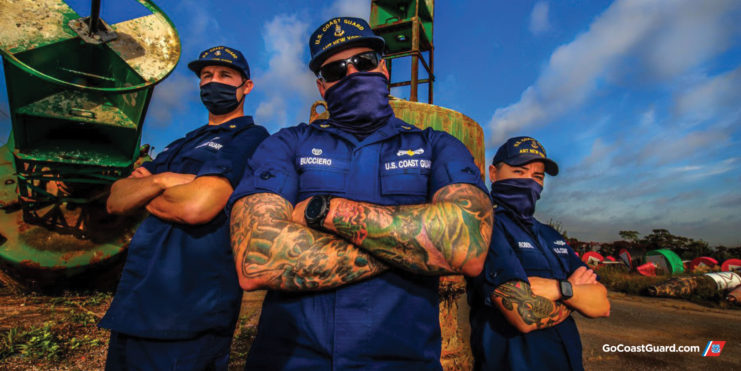 Three US Coast Guard crew members with their arms crossed over their chests
