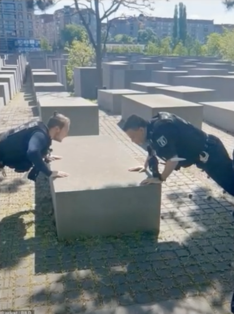 Two Berlin police officers leaning against a concrete slab