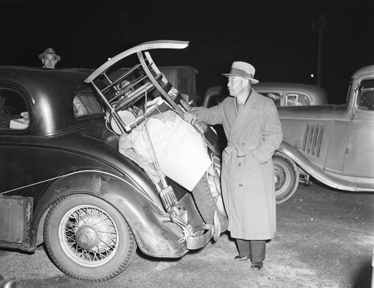 Japanese-American man standing behind a car trunk with a wooden chair in it