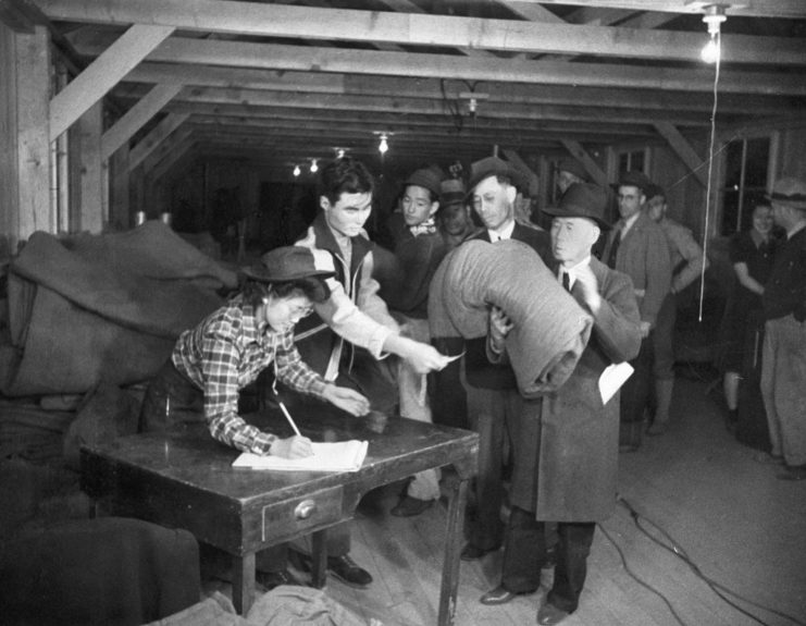Japanese men standing before a table while holding their personal belongings