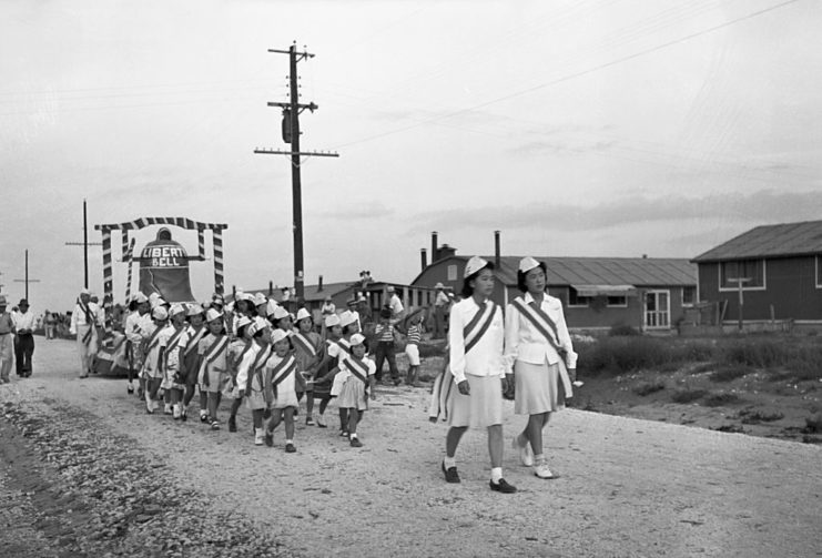 Japanese-American females walking ahead of a Liberty Bell parade float