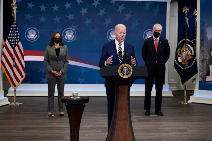 Joe Biden speaking at the Presidential podium while Kamala Harris and Denis McDonough stand behind him