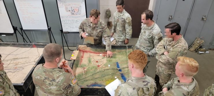 US Army Sniper School trainees gathered around a terrain map