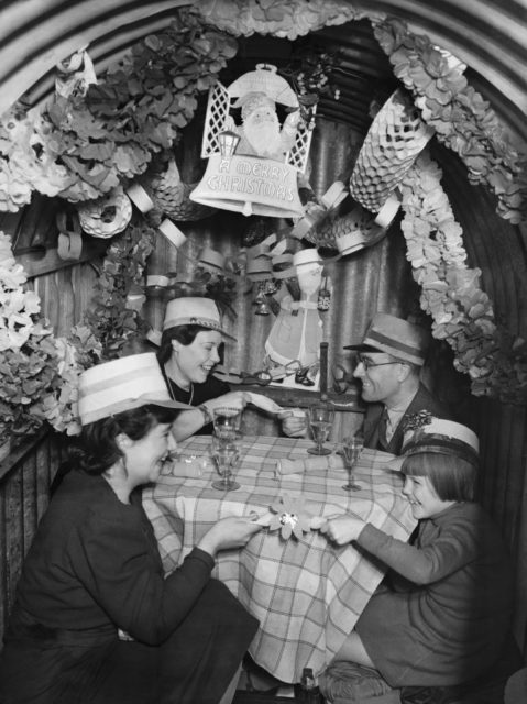 Family sitting around a table in an air raid shelter decorated for Christmas
