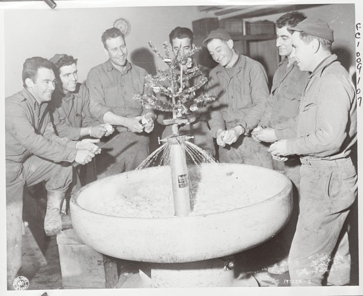 American soldiers standing around a sink while they peel potatoes