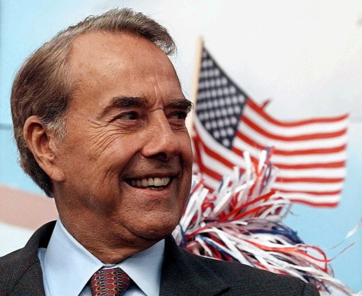 Bob Dole standing in front of an image of the American flag