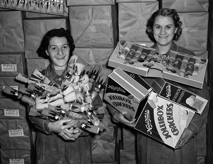 Two women holding armfuls of Christmas decorations