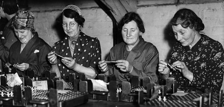 Four women filling munitions at a table