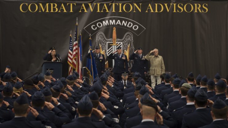 Combat Aviation Advisors saluting their leaders who stand on stage