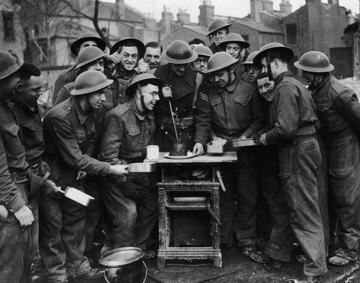 Soldiers gathered around a table with Christmas pudding