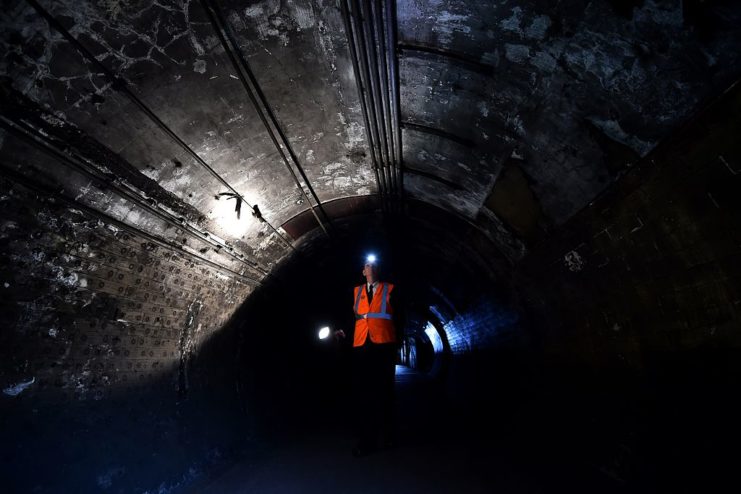 Male worker walking along a dark tunnel