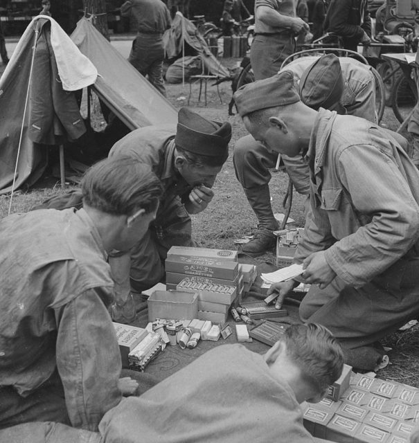 Soldiers crouched over a pile of boxed rations
