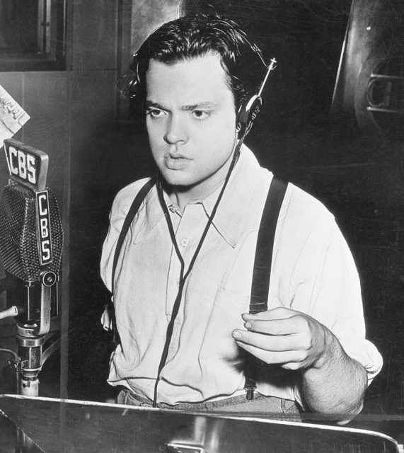 Orson Welles standing behind a microphone