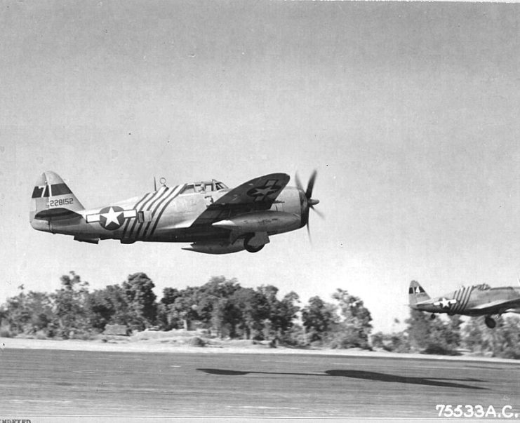 Two P-47 Thunderbolts flying above the ground