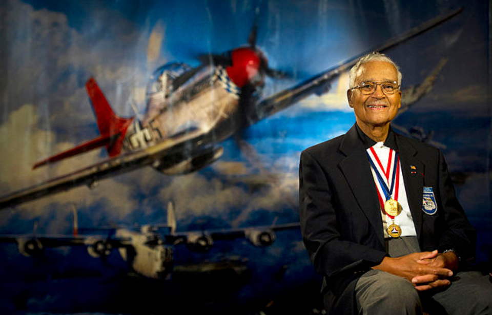 Charles McGee sitting in front of a painting of an airplane
