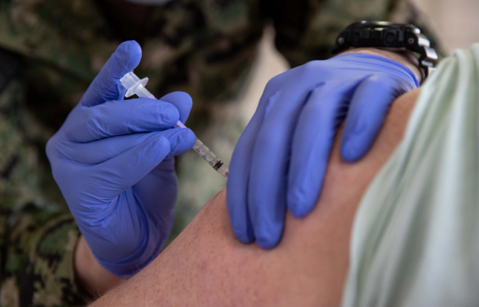 Hospital Corpsman 3rd Class Joseph Casassa administering a COVID-19 vaccine