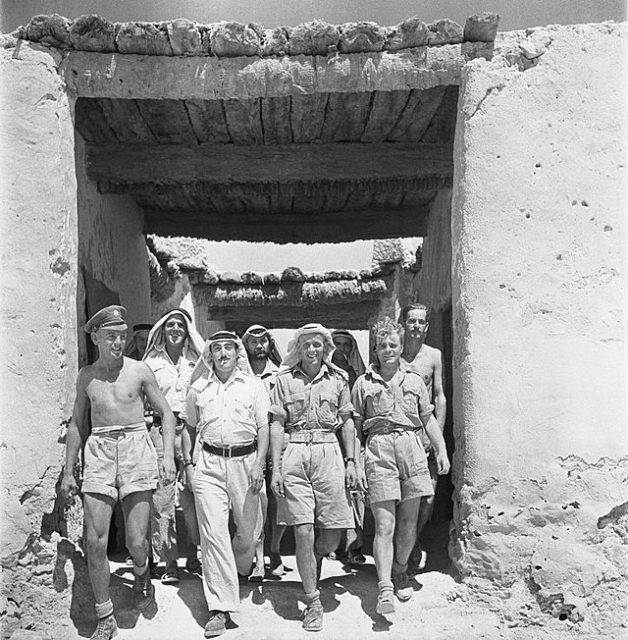Members of the Long Range Desert Group walking through a square archway