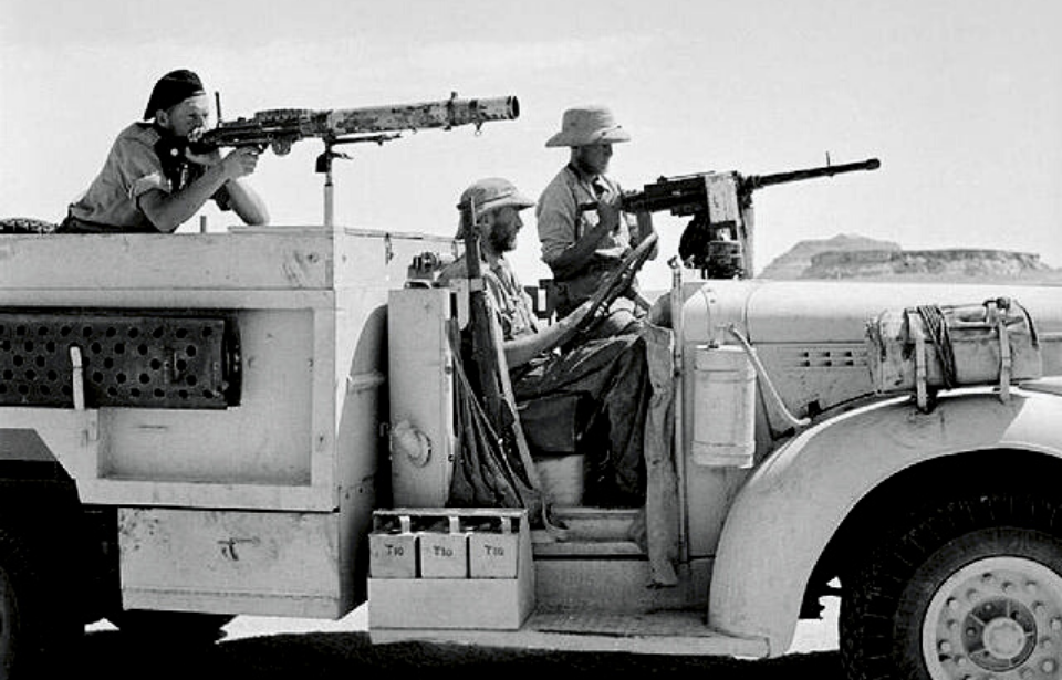 Three members of the Long Range Desert Group pointing guns while riding in a Chevrolet truck