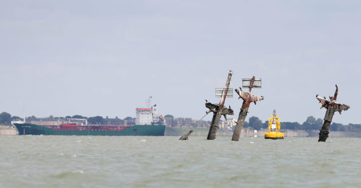 Freighter sailing behind the masts of the sunken SS Richard Montgomery
