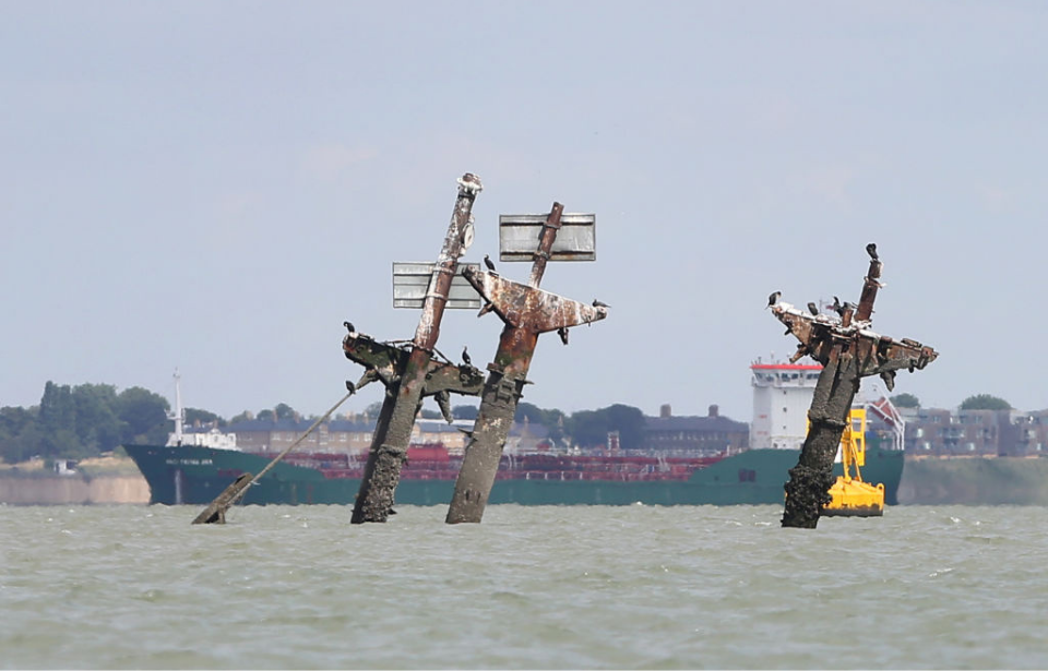 Freighter sailing behind the three masts of the sunken SS Richard Montgomery