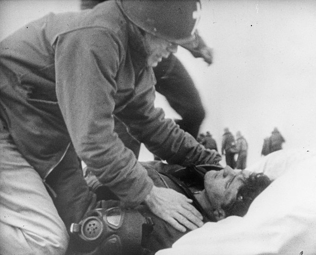 US Navy Chaplain leaning over an injured sailor