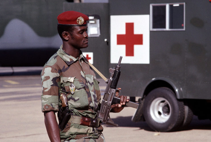 A member of the Armed Forces of Niger holding an Uzi while standing next to a mobile medical unit